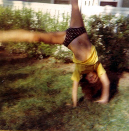 A young Rebecca doing a handstand in the yard